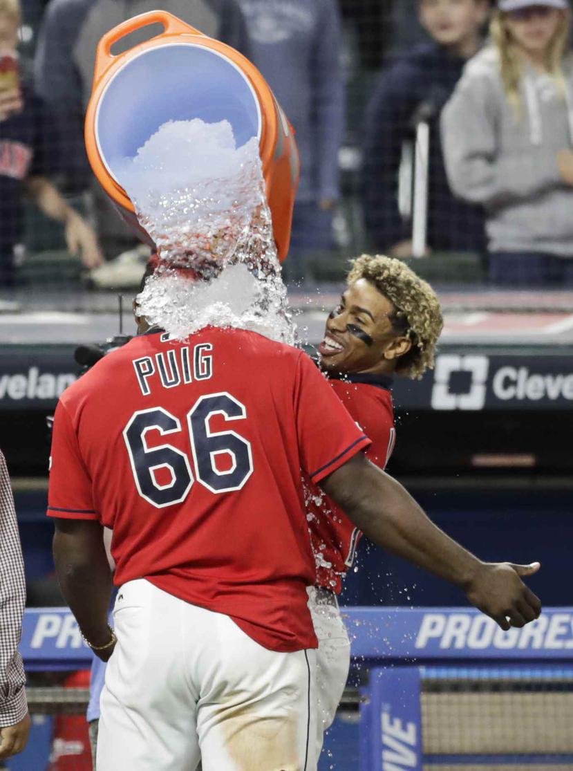 El jugador de los Indios de Cleveland, el puertorriqueño Francisco Lindor, vierte agua con hielo sobre su compañero, el cubano Yasiel Puig, quien conectó el sencillo que produjo la carrera ganadora en el décimo inning. (AP)