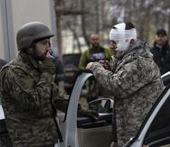 Un hombre herido habla con un soldado, izquierda, tras ser evacuado de Irpín, el miércoles 30 de marzo de 2022, en las afueras de Kiev, Ucrania.