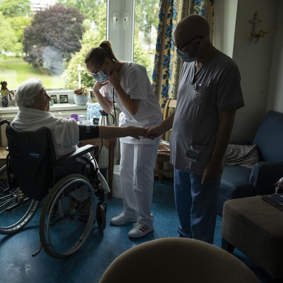 Nurse Jean-Claude Feda, right, and trainee Lyson Rousseau, center, both wearing face masks, to protect against the spread of coronavirus, measure the blood pressure of resident Odette Defraigne-Schmit at CHC Liege Mativa home for elderly people in Liege, Belgium, Thursday, July 9, 2020. While no coronavirus, COVID-19 patients, have been reported at this particular home, Belgium has been hard hit by the deadly virus. Elderly people living in retirement homes have accounted for nearly half of the total deaths in this small country with 11 million inhabitants. (AP Photo/Francisco Seco)