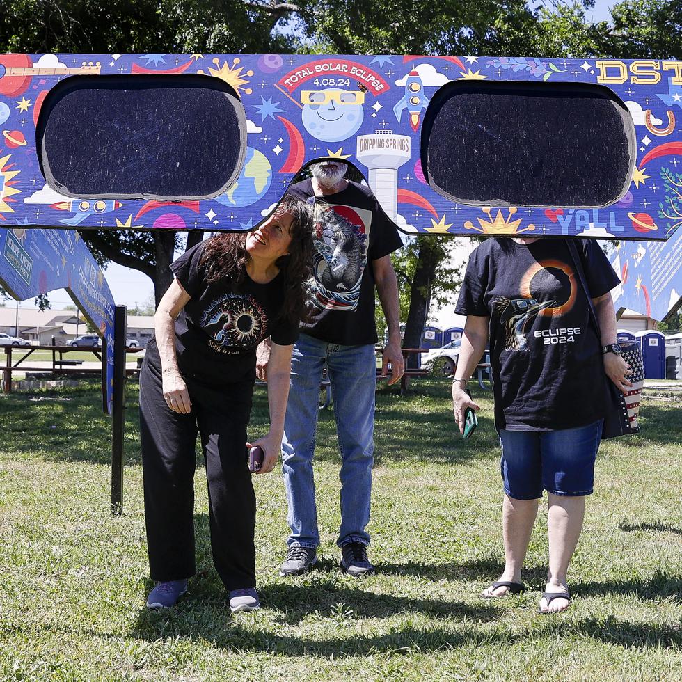 Una familia mira a través de un par de gafas gigantes especiales para el eclipse solar en el Veterans Memorial Park en Dripping Springs, Texas.