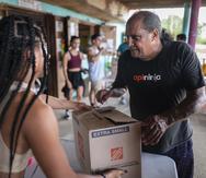 Héctor Cintrón, residente de Pozuelo, recibe una caja con suministros de emergencia y comida preparadas por voluntarios.