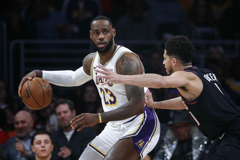 LeBron James, de los Lakers de Los Ángeles, intenta mover el balón ante la presión de su rival de los Suns de Phoenix Devin Booker. (AP)