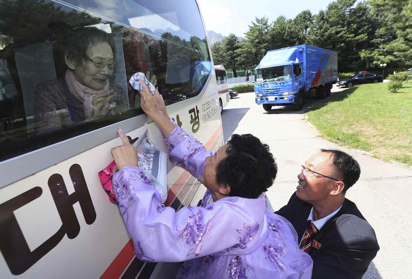 La norcoreana Kim Kyong Sil toca la ventana de un autobús para depedirse de su madre surcoreana, Han Shin-ja, de 99 años, tras una reunión familiar en el balneario de Diamond Mountain, en Corea del Norte. (AP)