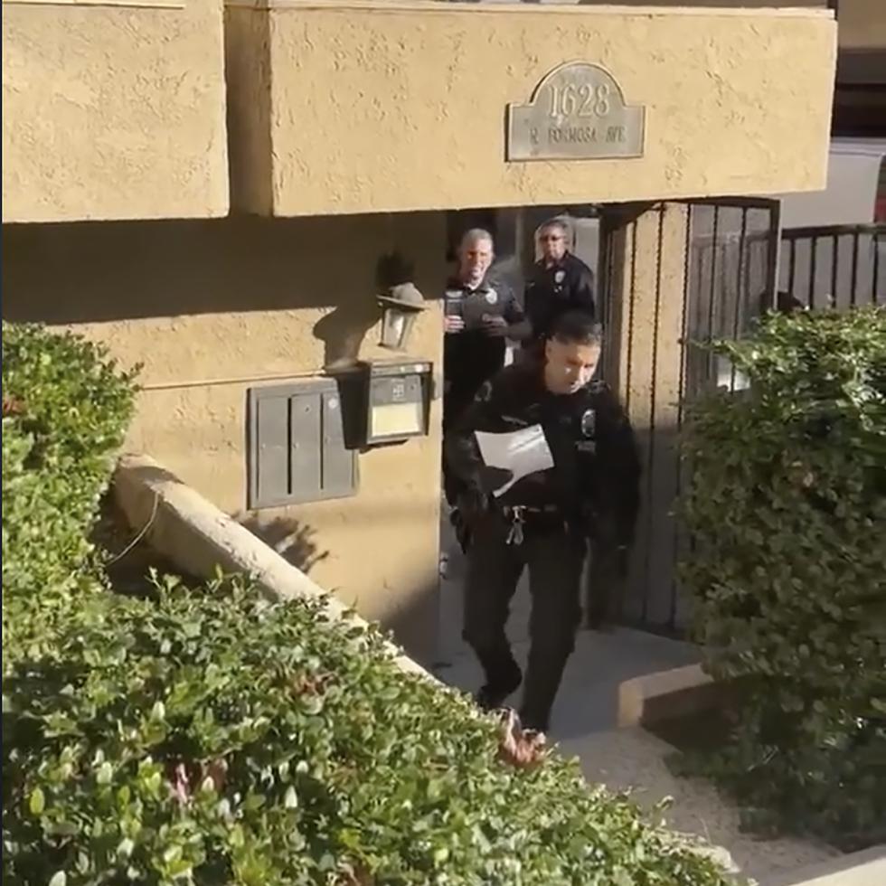 En esta captura de imagen tomada de un video proporcionado por el abogado Dermot Givens, agentes del Departamento de Policía de Los Ángeles se acercan a Givens con una copia de una orden de registro fuera de su casa, en Los Ángeles.