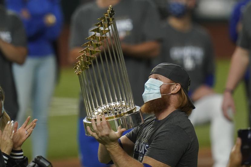 Tras arrojar positivo a COVID-19, Justin Turner, de los Dodgers de Los Ángeles, festeja con el trofeo de la Serie Mundial, tras el triunfo sobre los Rays de Tampa Bay.