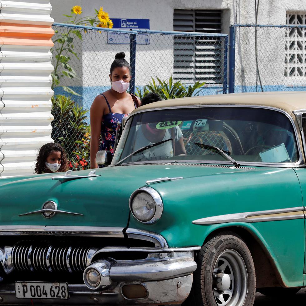 Personas con tapabocas se bajan de un auto clásico, este lunes en La Habana, Cuba.