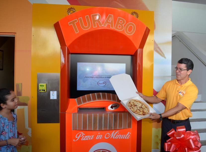 El ingeniero Edwin Alejandro, quien adquirió los derechos de la dispensadora para Puerto Rico, muestra la pizza recién horneada que despacha la máquina en su propia caja. (Suministrada)