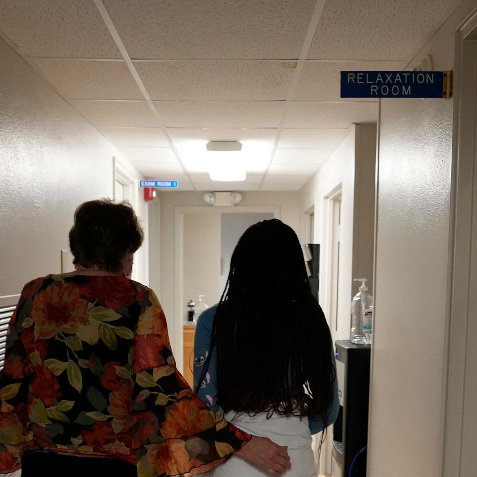 A 33-year-old mother of three from central Texas is escorted down the hall by clinic administrator Kathaleen Pittman prior to getting an abortion, Saturday, Oct. 9, 2021, at Hope Medical Group for Women in Shreveport, La. The woman was one of more than a dozen patients who arrived at the abortion clinic, mostly from Texas, where the nation's most restrictive abortion law remains in effect. (AP Photo/Rebecca Blackwell)