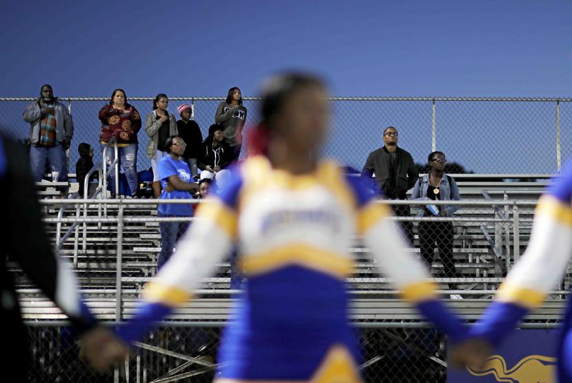 Espectadores se ponen en pie para el escuchar el himno de Estados Unidos antes de un partido en la escuela secundaria South Robeson de Rowland, Carolina del Norte, mientras las porristas se hincaron de rodillas. (AP)