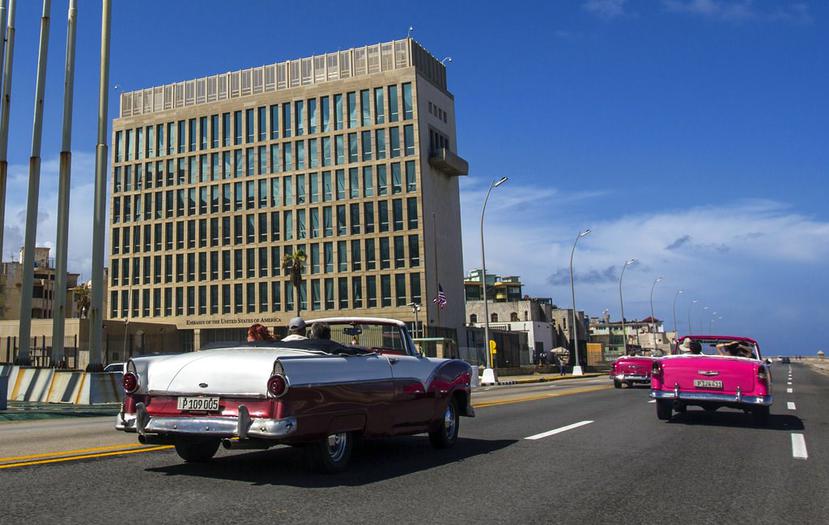 Turistas a bordo de un auto clásico descapotable pasan por el Malecón de La Habana, frente a la embajada de Estados Unidos en la capital cubana. (AP/ Desmond Boylan).