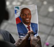 Una imagen de archivo que muestra a una persona que sostiene una fotografía del difunto presidente Jovenel Moïse durante una ceremonia fúnebre el 20 de julio de 2021, en el Museo y Cementerio Nacional, en Puerto Príncipe, Haití.