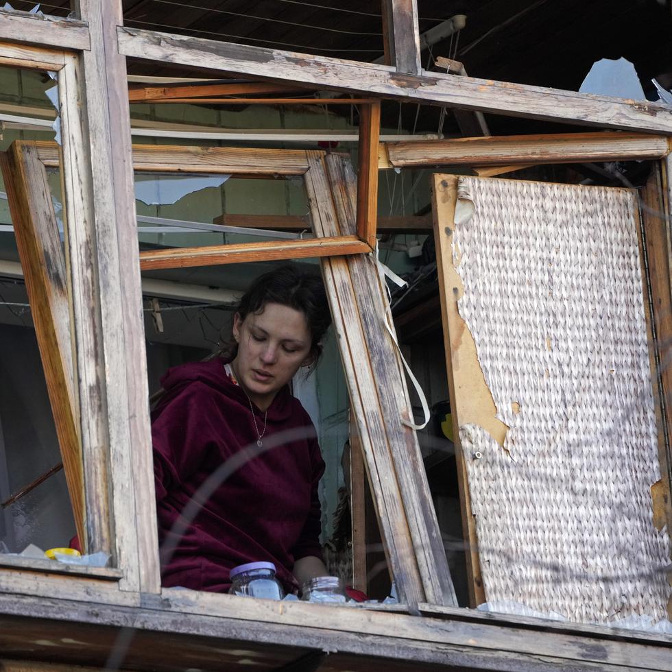 Una mujer está cerca de una ventana rota en su apartamento tras un ataque ruso en Kiev, Ucrania, el lunes 14 de marzo de 2022. (AP Foto/Efrem Lukatsky)