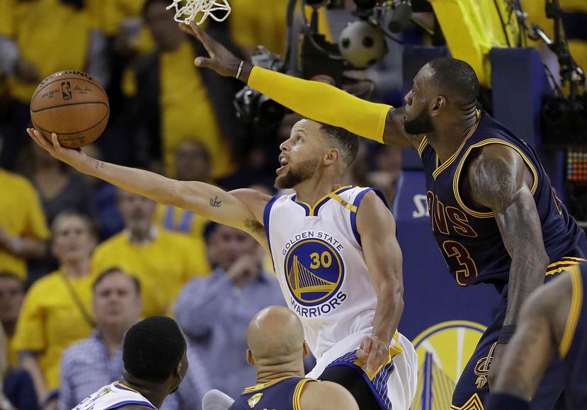 El líder de los Cavaliers, LeBron James, intenta quitarle el balón a Stephen Curry, de los Warriors. (AP)