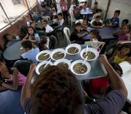 Un grupo de niños miran su comida gratis en un comedor social auspiciado por la oposición en Caracas, Venezuela. (AP)