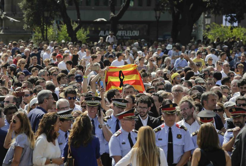 Una multitud de personas, entre las que sobresale una bandera de Cataluña con un crespón negro, se reúnen para guardar un minuto de silencio en memoria de las víctimas del ataque extremista en Las Ramblas. (AP)