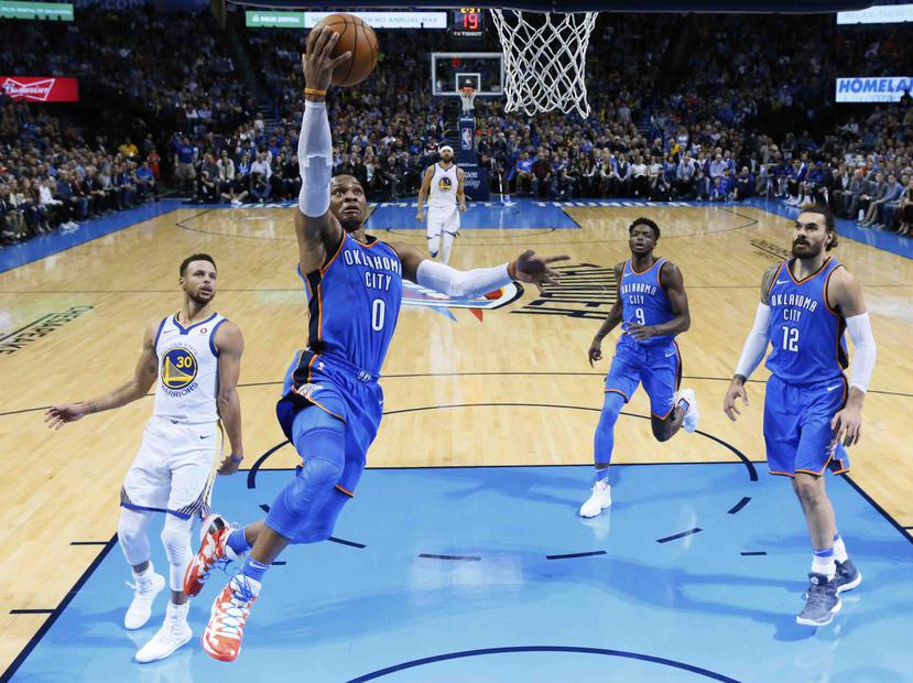 Russell Westbrook, se apresta a marcar un canasto tras burlar la defensa de Stephen Curry, de los Warriors de Golden State. (AP / Sue Ogrocki)