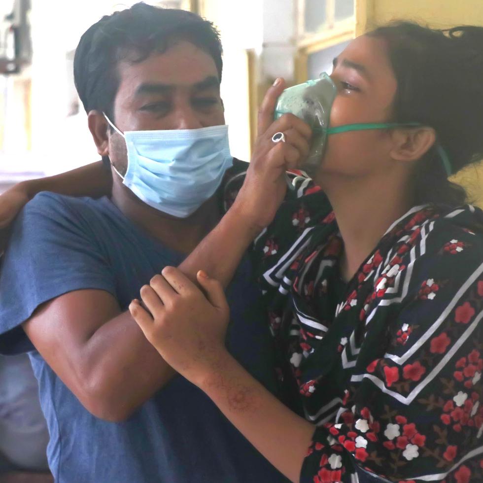 Un hombre asiste a una paciente con dificultad para respirar en el Medical College Hospital, en la ciudad de Rajshahi, en Bangladesh, localidad donde están en aumento los contagios de COVID-19 vinculados a la variante Delta.