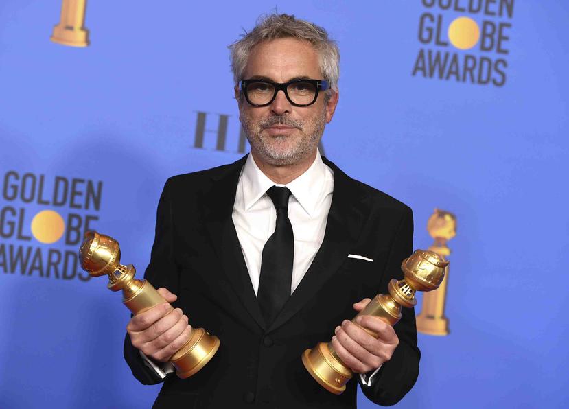 El director del filme "Roma", Alfonso Cuarón, sostiene las dos estatuillas que ganó. (AP)