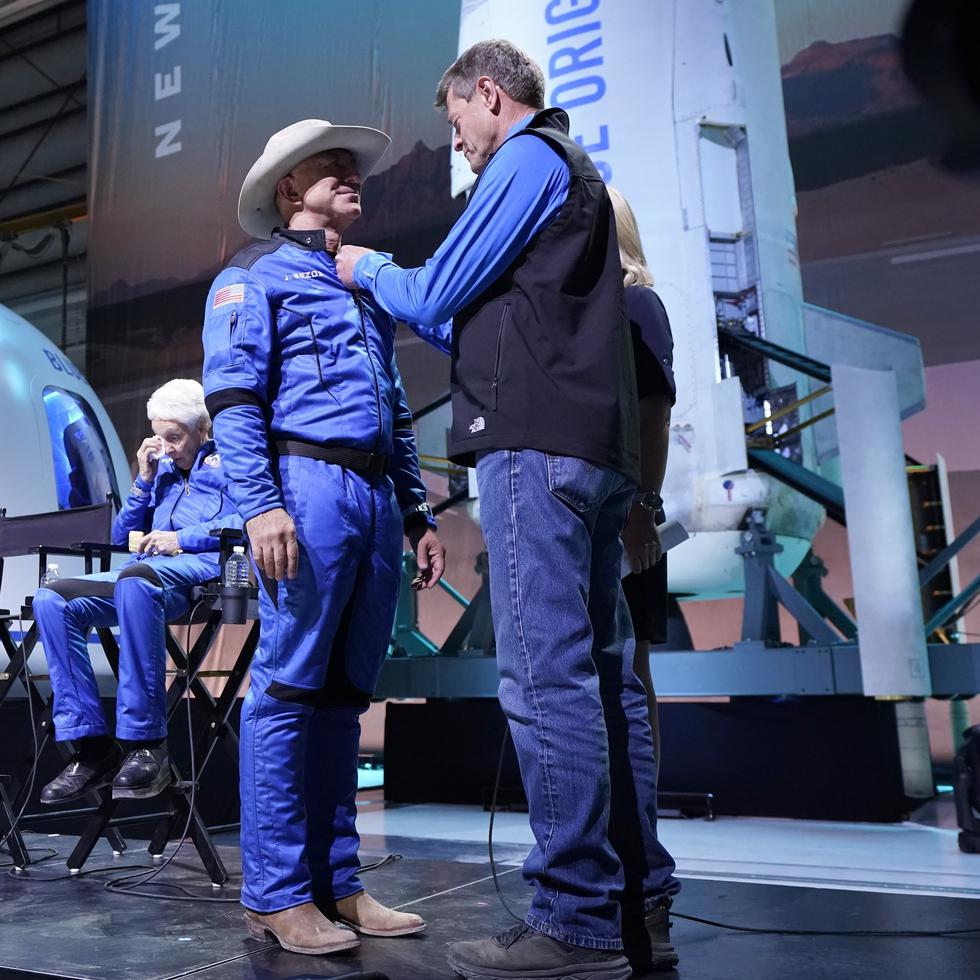 Desde la izquierda, Oliver Daemen, Mark Bezos y Wally Funk presencian cuando Jeff Bezos, segundo desde la derecha, recibe su insignia de alas de astronauta elaborada por Blue Origin de manos del exastronauta de la NASA, Jeff Ashby, a la derecha, quien ahora está con Blue Origin.