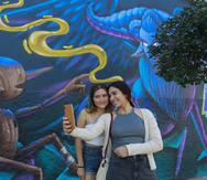 Dos mujeres se toman una foto junto a un mural inspirado en la película "Pinocchio" del cineasta mexicano Guillermo del Toro.