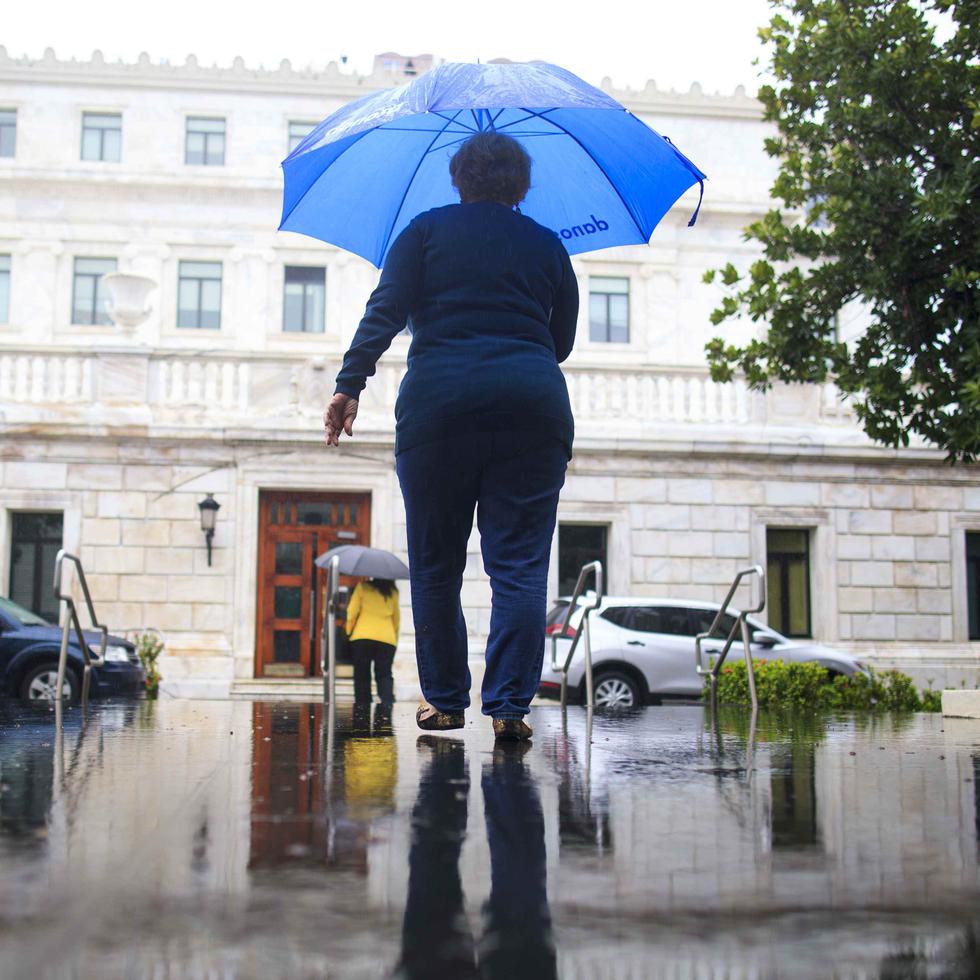 Una mujer utiliza un paraguas para no mojarse en la lluvia.
