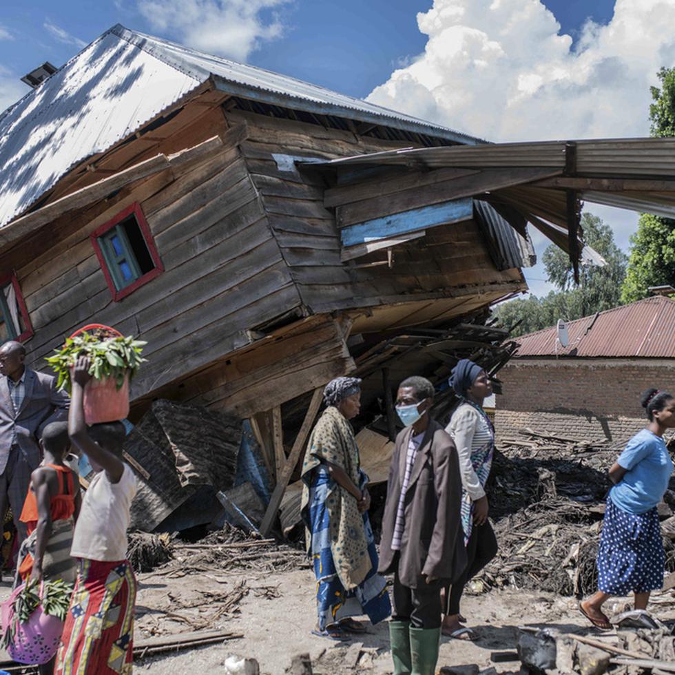 La gente camina junto a una casa destruida por las inundaciones en la aldea de Nyamukubi, provincia de Kivu del Sur, en la República Democrática del Congo, el sábado 6 de mayo de 2023. (Foto AP/Moisés Sawasawa)