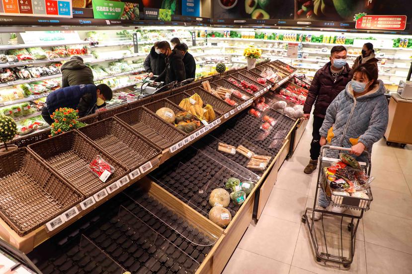 Arriba, compradores en mascarillas caminan por góndolas casi vacías en un supermercado en Wuhan, en la provincia central china de Hubei, el pasado 25 de enero. (EFE/EPA/YUAN ZHENG CHINA OUT)