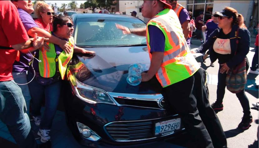 Un video difundido por Cohen muestra al auto abrirse paso por una fila de manifestantes que marchan en un cruce peatonal en una intersección. (AP)