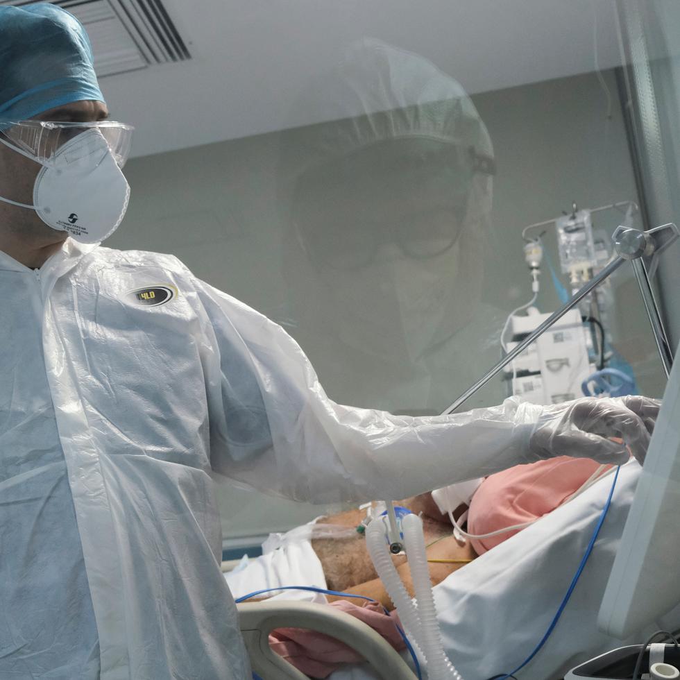 Un médico atiende a un paciente recluido en una Unidad de Cuidados Intensivos por complicaciones de COVID-19.