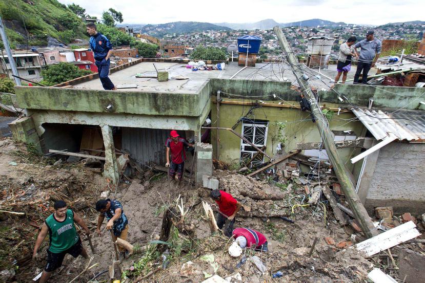Un grupo de personas retiran lodo y escombros en una zona de viviendas destruidas por un alud a causa de las fuertes lluvias. (AP/Alexandre Mota-Futura Press)