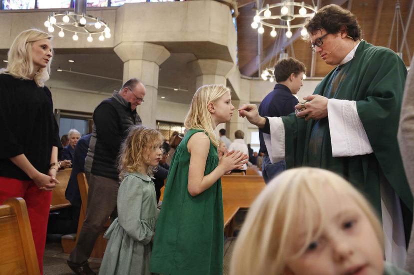 El reverendo Joshua Withfield toma la comunión a su esposa Alli y a las hijas de ambos Zoe-Catherine (izq), y Maggie en la iglesia Santa Rita de Dallas. (AP)