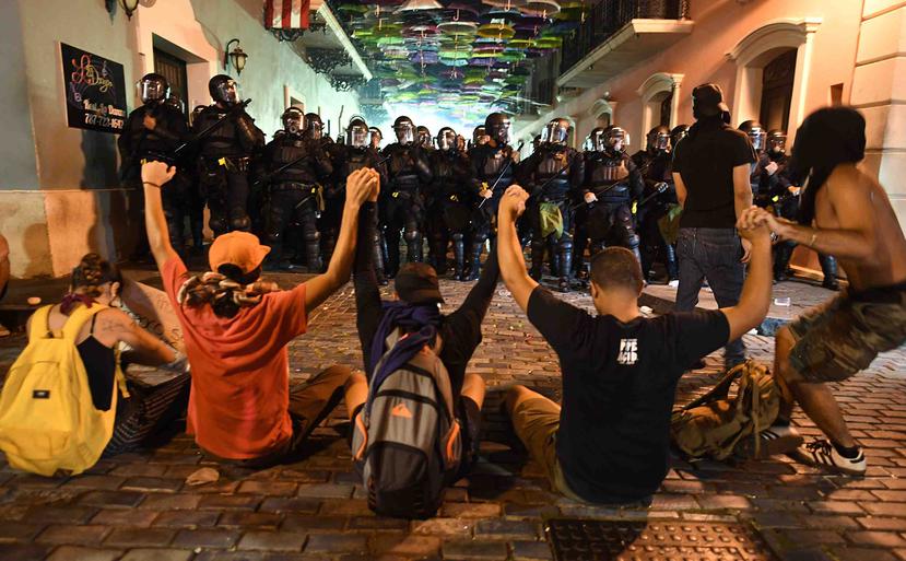 Varios manifestantes se sentaron en la calle, unidos de manos, ante el avance de oficiales de la Policía.