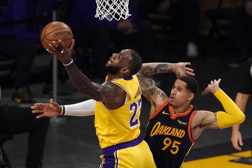 LeBron James, de los Lakers, realiza un incómodo tiro frente a Juan Toscano-Anderson, de los Warriors, en el partido "play-in" de la NBA.