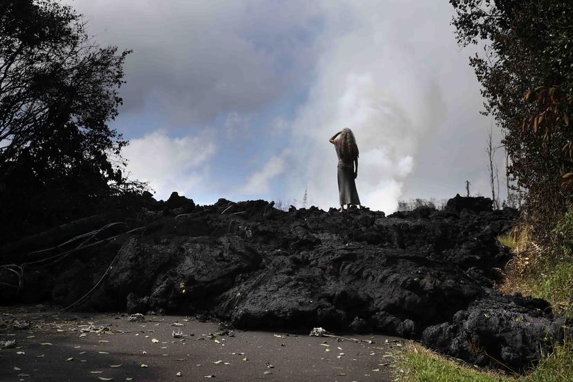 Hannique Ruder, una mujer de 65 años que vive en el vecindario Leilani Estates, permanece de pie sobre lava endurecida cerca de Pahoa. (AP)