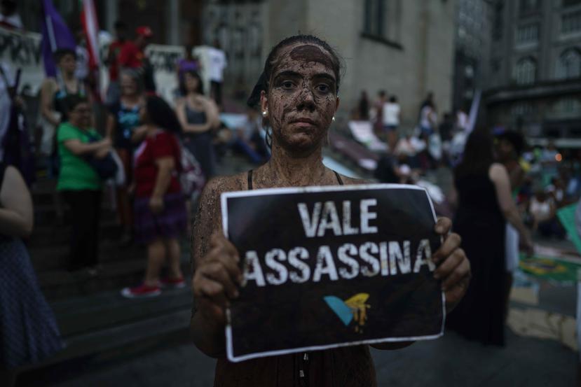 Una activista cubierta de lodo posa con un letrero que dice "Vale asesina", refiriéndose a la empresa minera Vale, durante una protesta en la catedral de Sao Paulo por la ruptura de una presa administrada por esa compañía, el viernes 1 de febrero de 2019.