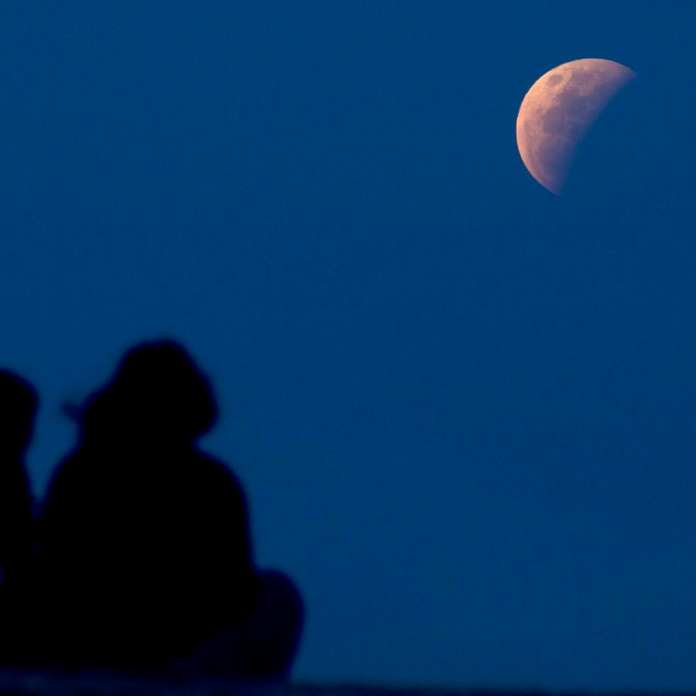 Una pareja en Sanur, Bali, localidad de Indonesia, observa el eclipse.