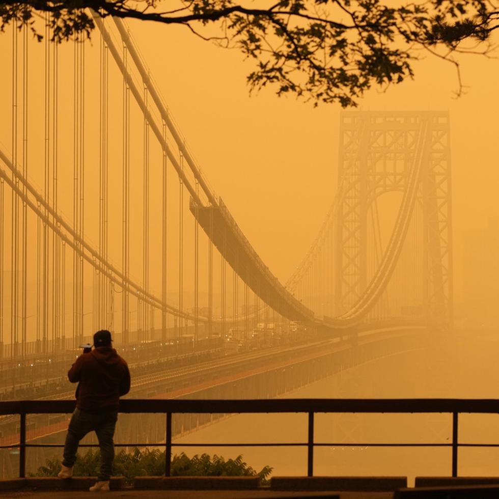 Un hombre conversa por su teléfono en medio de una bruma de humo cerca del puente George Washington causada por 1,000 incendios registrados en Canadá que destruyeron 58,000 millas cuadradas de terreno.