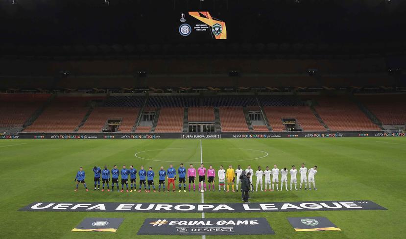 Jugadores del Inter, izquierda, y del Ludogorets forman una fila en un vacío estadio San Siro de Milán, Italia, previo a su juego de vuelta por los 16vos de final de la Liga Europa, el pasado 27 de febrero de 2020.  (Emilio Andreoli, UEFA vía AP )