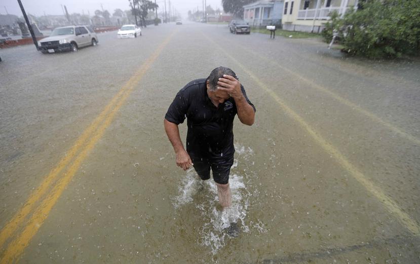 Un hombre camina por una de las calles en Galveston, Texas, luego de que su carro quedara inundado por las fuertes lluvias. (AP)