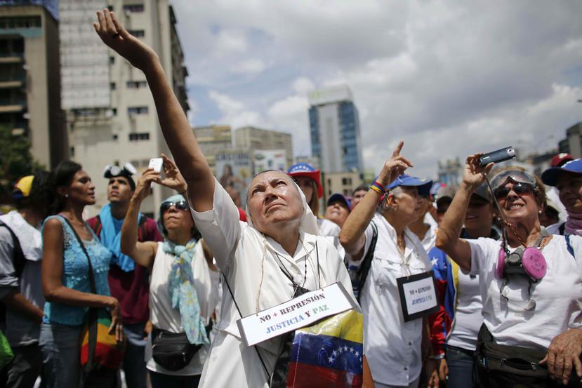 Una monja se encuentra ante un cordón de la Guardia Nacional Bolivariana bloqueando el paso a una marcha de mujeres de oposición, en una carretera en Caracas, Venezuela. (AP)