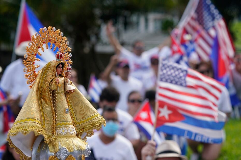 A small statue of Our Lady of Charity, the patron saint of Cuba, is held up as protesters gathered.