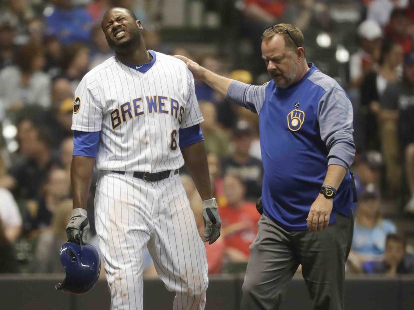 Lorenzo Cain de los Cerveceros de Milwaukee hace un gesto de dolor tras ser golpeado. (AP)