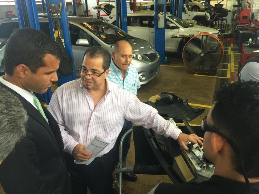 El titular de DACO, Michael Pierluisi (izq.) observa mientras Roberto de la Torre (centro) hace una demostración de los trabajos de reparación en los vehículos Toyota. (Suministrada)