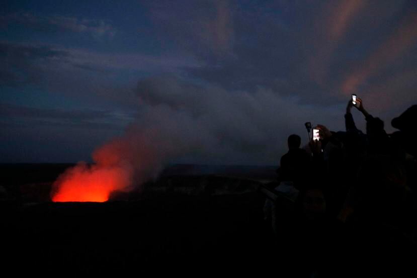 Visitantes toman fotos del resplandor rojo del volcán Kilauea. (AP)