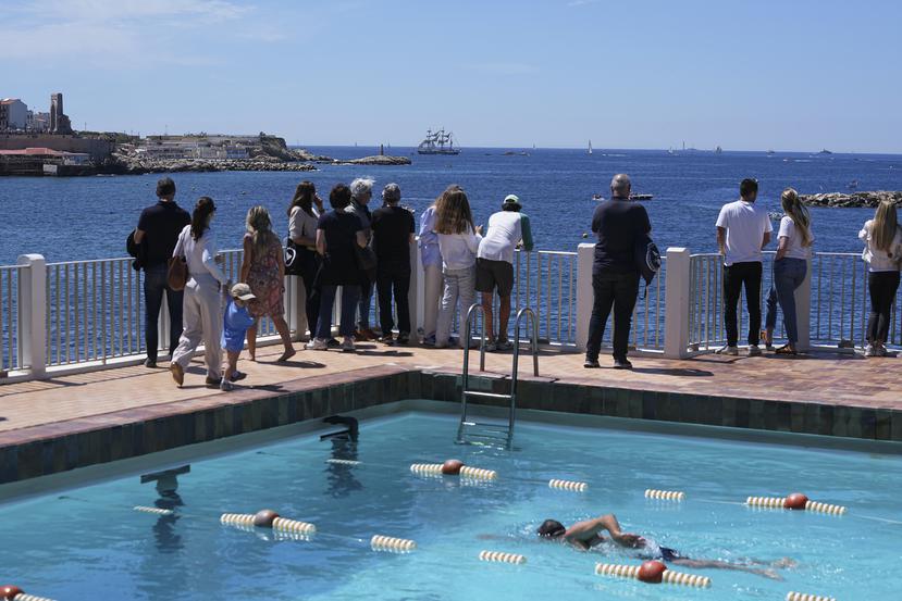 Un grupo de personas frente a una piscina olímpica aguarda el arribo del Belem, el velero con la llama de los Juegos Olímpicos de París.