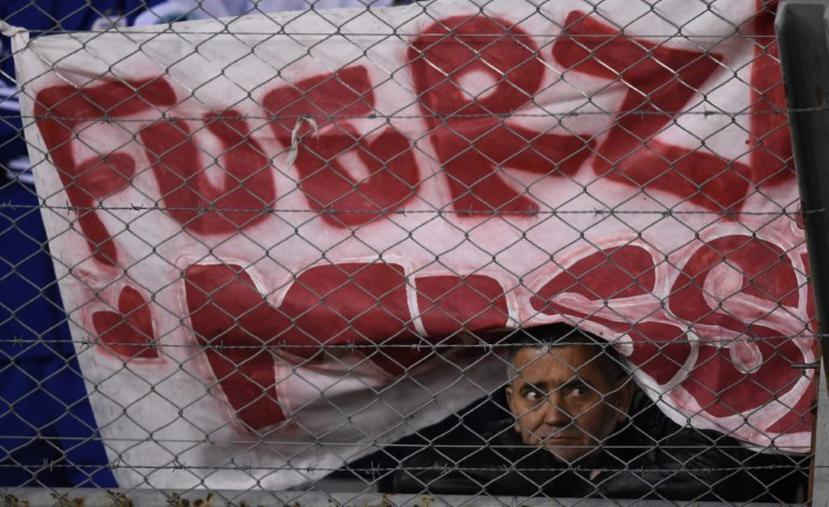 Un fanático argentino boserva debajo de un cartel en apoyo a Messi.