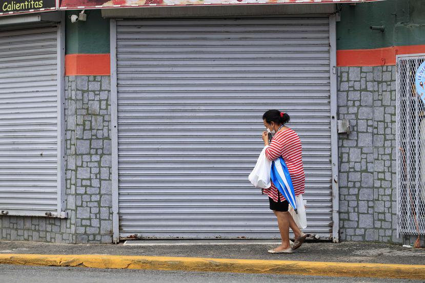 Una mujer pasa frente a un local cerrado en San Juan.