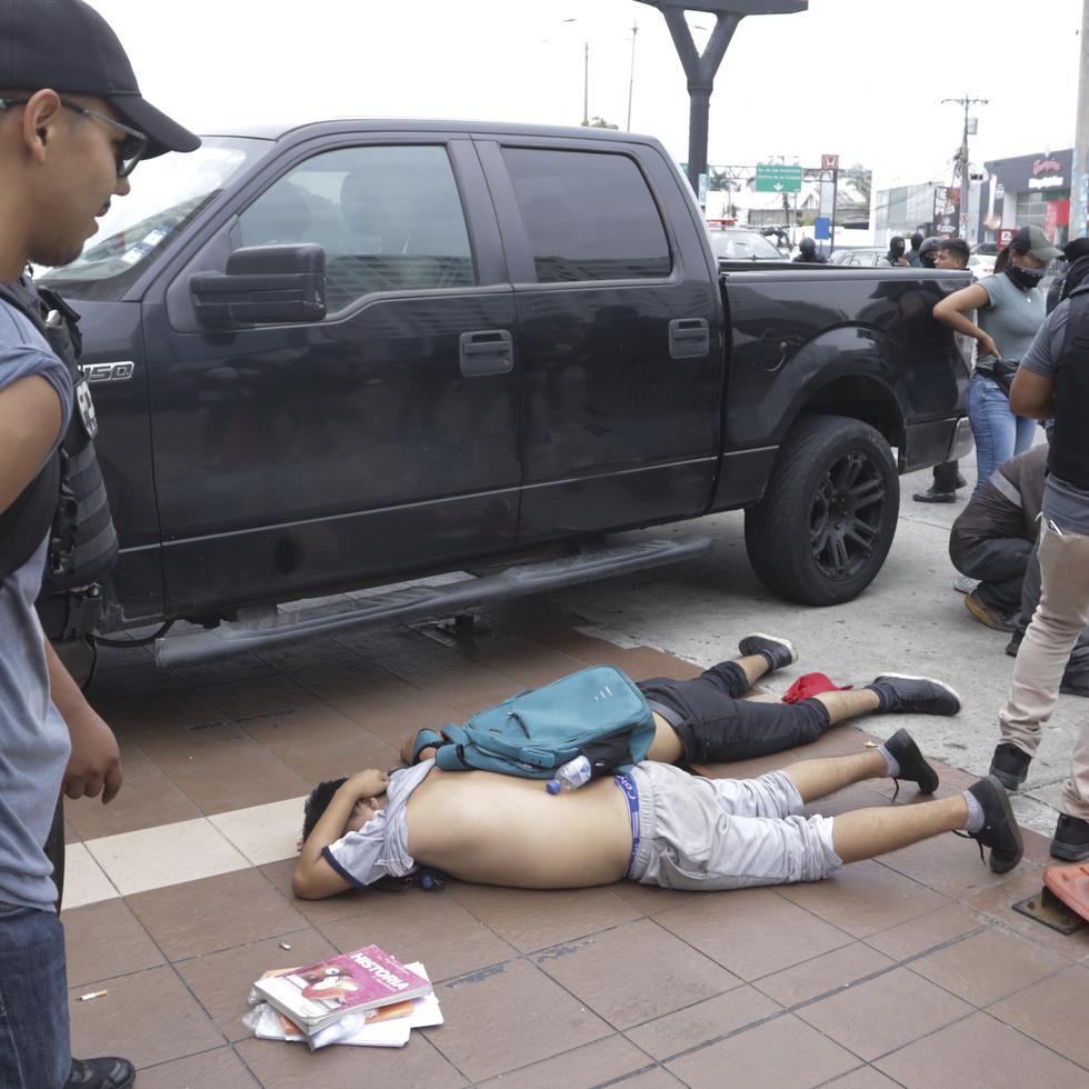 Hombres yacen boca abajo en el suelo detenidos por policías afuera de los estudios de TC Televisión, en Guayaquil, luego de que un productor le dijera a la policía que formaban parte de un grupo que irrumpió en su set durante una transmisión en vivo.