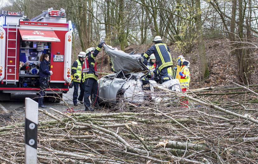 Rescatistas trabajan en un auto que quedó aplastado por un árbol caído durante una tormenta en Moers, en el oeste de Alemania. El conductor resultó herido de gravedad. (AP / Christoph Reichwein).