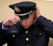 Dustin Boone se ajusta el sombrero antes de su ceremonia de graduación de la academia de policía de St. Louis en la Universidad Estatal Harris-Stowe.